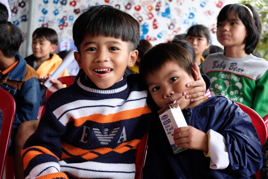 Nụ cười cùng ánh mắt vui tươi của hai cháu nhỏ mồ côi cả cha lẫn mẹ (cháu Ngô Gia Tự - Sinh năm 2012, mặc áo len và cháu Hồ Gia Huy - Sinh năm 2013, mặc áo gió) khi đón nhận quà từ Chương trình